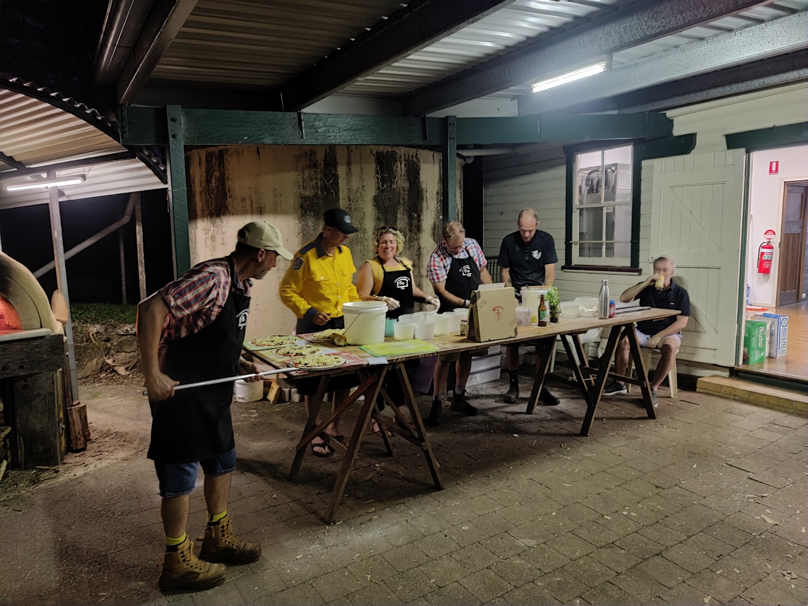 Volunteer sliding a pizza into the wood-fired oven