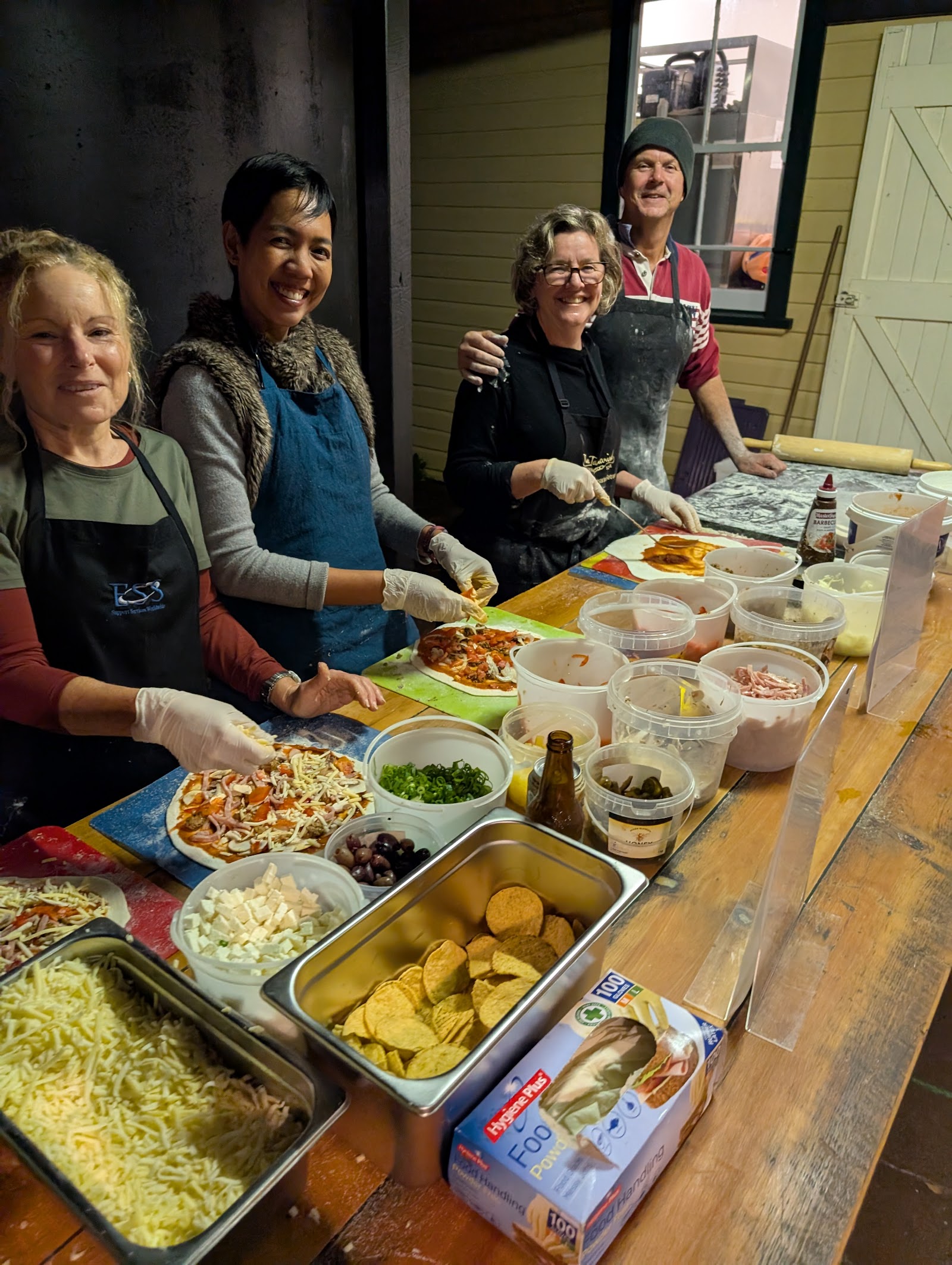 Smiling volunteers preparing pizzas